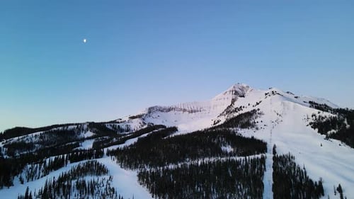 A drone shot of snowy Big Sky, Montana in winter, showcasing the ski resort and majestic mountain te
