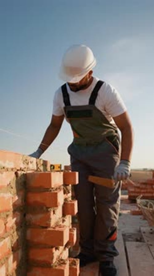Un constructor indio coloca cuidadosamente ladrillos en el sitio de construcción