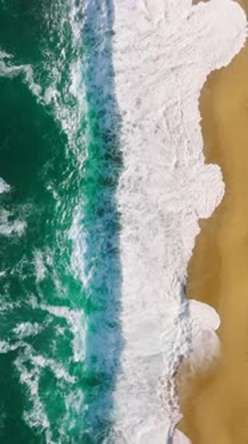 High Angle Shot of Waves Crashing on a Golden Sandy Beach