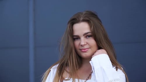 Portrait of young Caucasian girl in white shirt posing for camera. Close-up
