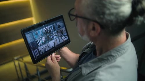 Male Installer Watches CCTV Cameras in Stylish Office Using Tablet Computer