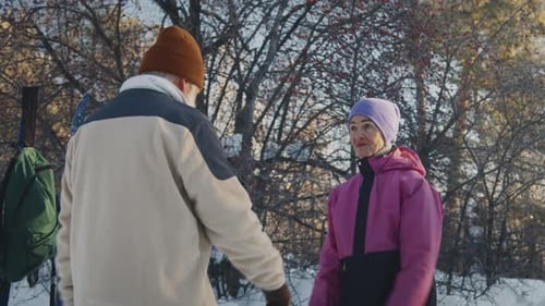 Cheerful Senior Couple Warming Up in Forest before Ski Hike