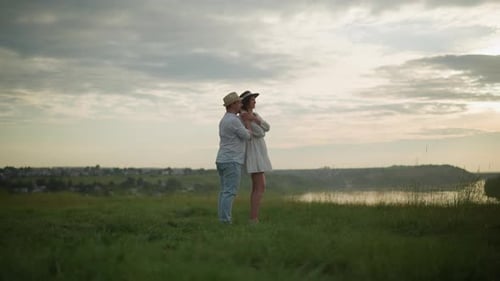 Sweethearts Embracing on a Grassy Hill at Sunset