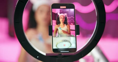 Mujer, teléfono móvil y anillo de luz para grabar, proyectar y transmitir en vivo para una influencer cosmética