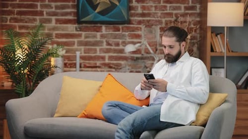 Man Using Mobile Phone on Couch at Home