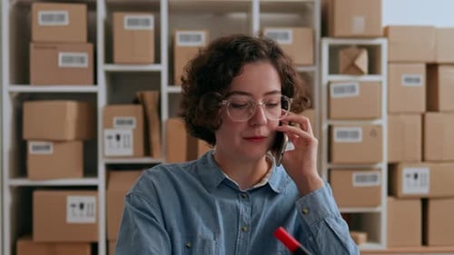 Woman Talks on Phone While Writing on Package