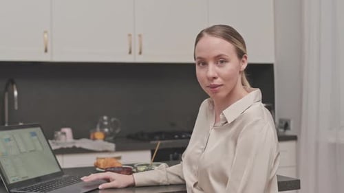 Young Woman Using Laptop in Bright Kitchen