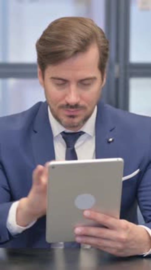 Man in Suit Using Tablet at Desk Indoors