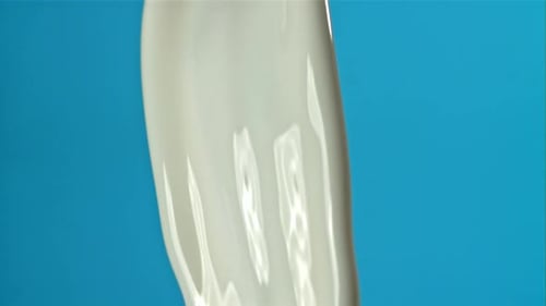 Milchspritzer auf blauem Hintergrund, gefilmt mit einer Hochgeschwindigkeitskamera mit 1000 Bildern pro Sekunde