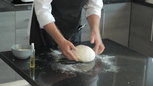 Chef Kneading Dough on Counter in Modern Kitchen