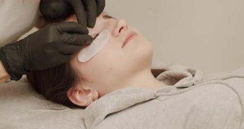 Beautician Eyelash Extension for Young Woman in a Beauty Salon