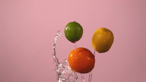 Citrus Fruit Falling In Slow Motion Against Pink Background