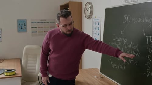 Professeur pointant vers un tableau noir avec des notes sur les bases de la modélisation 3D, donnant une conférence