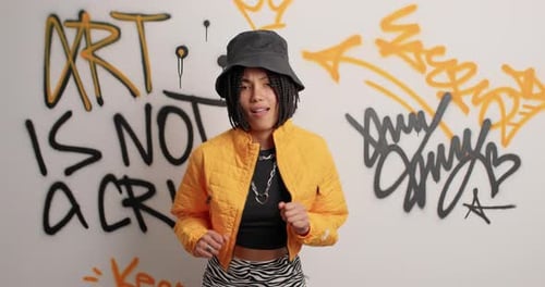 Stylish woman posing in front of graffiti wall