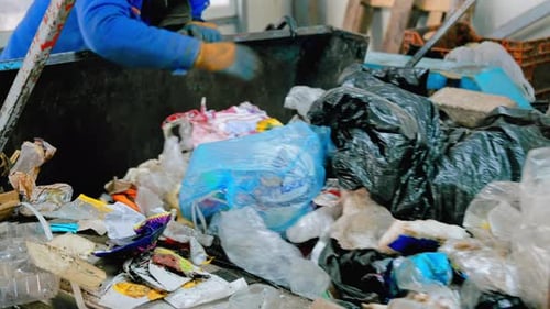 Employee working with garbage moving on a conveyor belt at waste sorting plant
