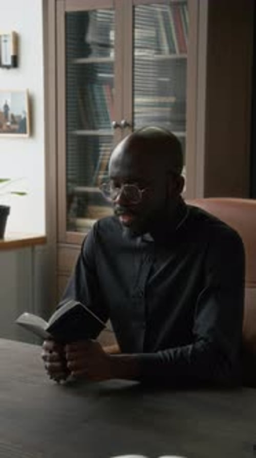 Man Sitting at a Table Reading a Book