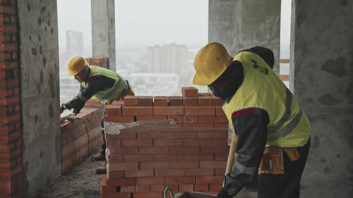 Construction Workers Building a Brick Wall Indoors