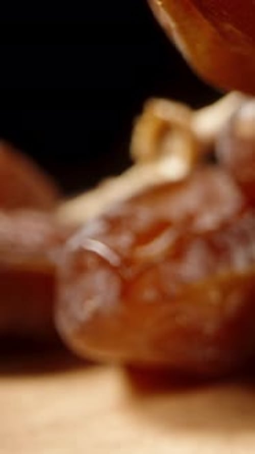 Vertical video. Dried dates are arranged on a wooden table. Dolly