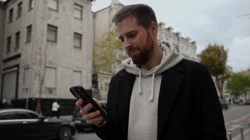 Attractive man in coat in the city is chatting on the phone and smiling