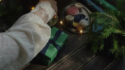 Woman wrapping Christmas Gift on Wooden Table