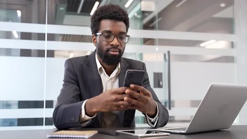 Young Professional Using Mobile Phone at Office Desk