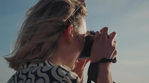 Plan rapproché d'une jeune femme avec appareil photo, prenant des photos du bord de mer au bord de l'océan.