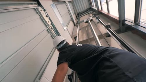 Young man mechanic engineer working doing maintenance on elevator lift at construction site slow mot