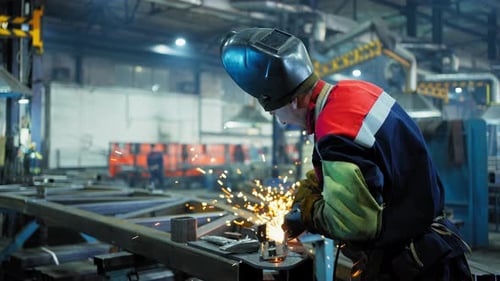 Professioneller Schweißer, der in der Fabrikwerkstatt der Fabrik arbeitet, mit einem männlichen Techniker beim Schweißen