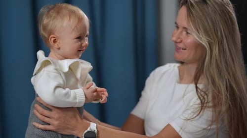 Joyful Little Baby Girl Smiling As Woman Talking to Kid in Slow Motion Standing Indoors