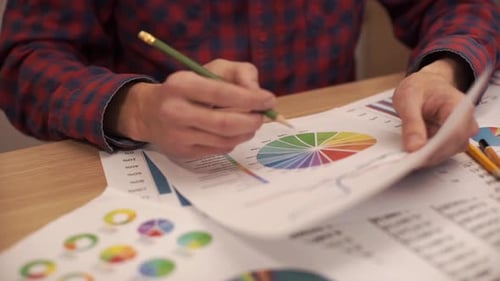 Adult Works With Charts and Graphs at Work