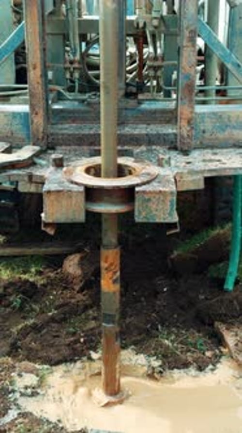 Digging a hole in ground with rig machine. Water drilling equipment. Vertical video.