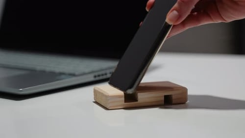 Women's Hand Takes Phone From the Wooden Phone Holder