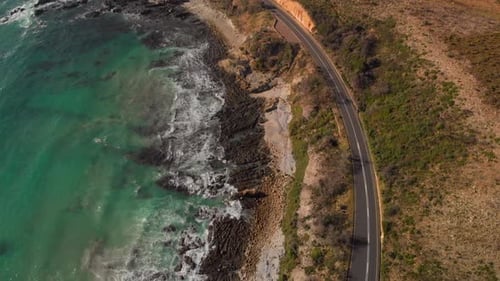 Aerial drone view of camera pan up from coastal road to mountain pass and ocean view