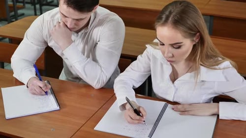 Os alunos se sentam em suas mesas e fazem anotações sobre a palestra