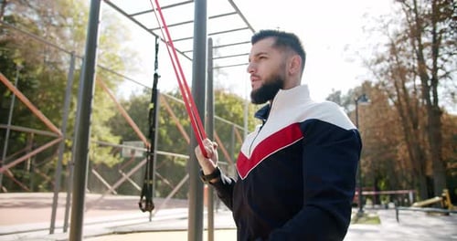 Man Exercising with Resistance Band in Outdoor Gym