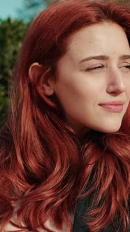 Vidéo verticale, femme rousse heureuse se relaxant dans le parc