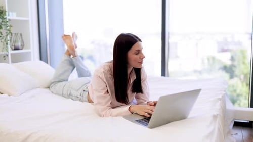 Attraktive Frau arbeitet aus der Ferne von zu Hause aus und tippt auf einem modernen kabellosen Laptop