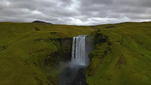 cinematic drone footage of Skógafoss Waterfall in Iceland, capturing the immense curtain of water