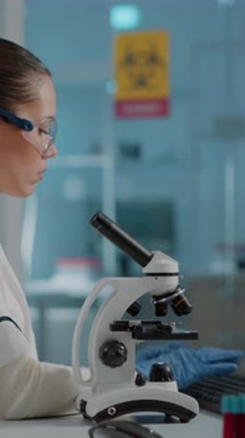 Woman Works with Microscope in Bright Medical Lab