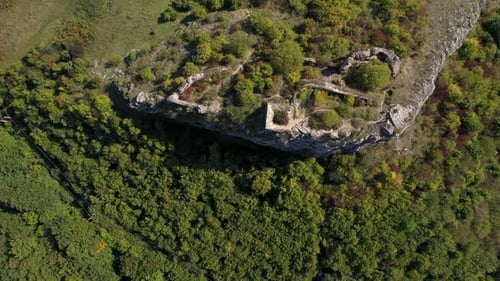 Aerial view of medieval fortification ruins, on a cliff in the forest by drone