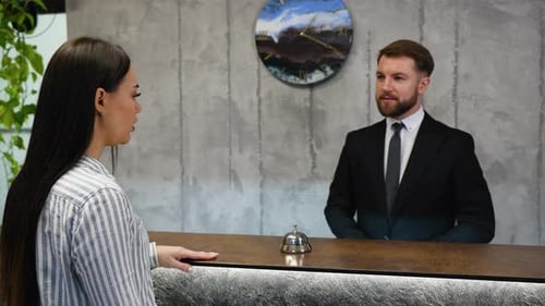Woman Guest Checking in at a Hotel Reception Desk