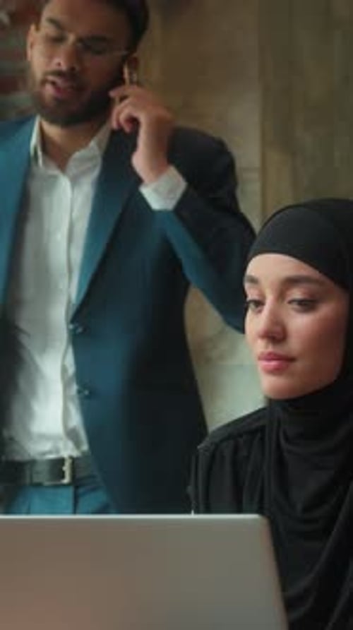 Woman works as man talks on phone in office