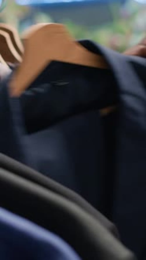 Vertical Video Man Browses Clothes Racks in Thrift Shop