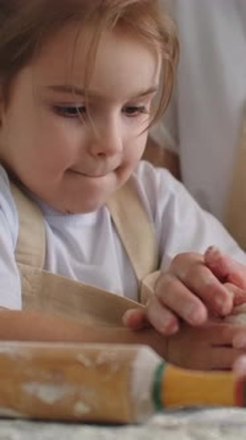 Young Child Learning to Bake with Adult Guidance Shaping Dough and Rolling Pastry Together in a Warm