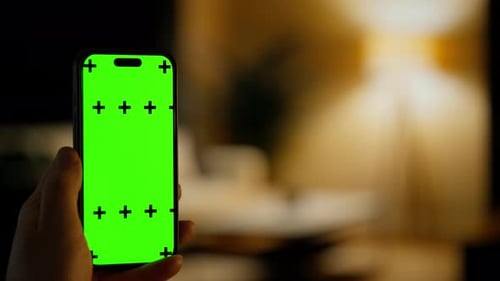 Hand Holding Smartphone with Bright Green Chroma Key Screen and Tracking Markers in Softly Lit