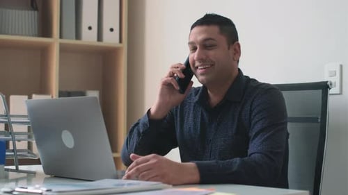 Cheerful Man Talking on Phone in Modern Office