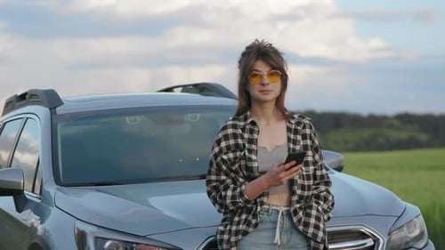 Smiling Woman with Phone Near Vehicle