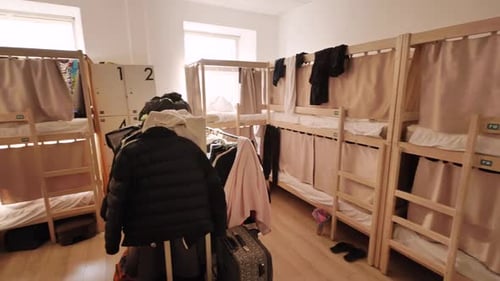 Modern Hostel Room Interior Showing Wooden Bunk Beds with Beige Curtains and Clothes Hanging