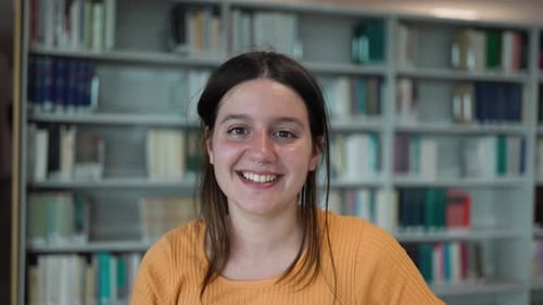 Happy young student smiling into the camera inside university library