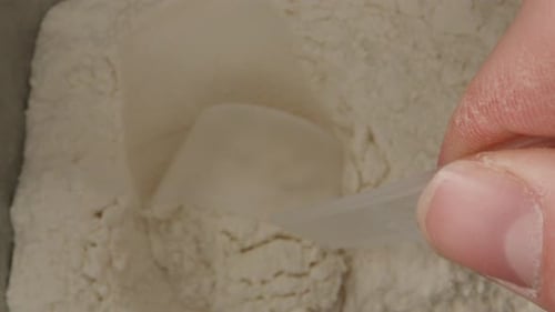 I take out a measuring spoon from a jar of flour, top view. Dolly slider extreme close-up inside. La